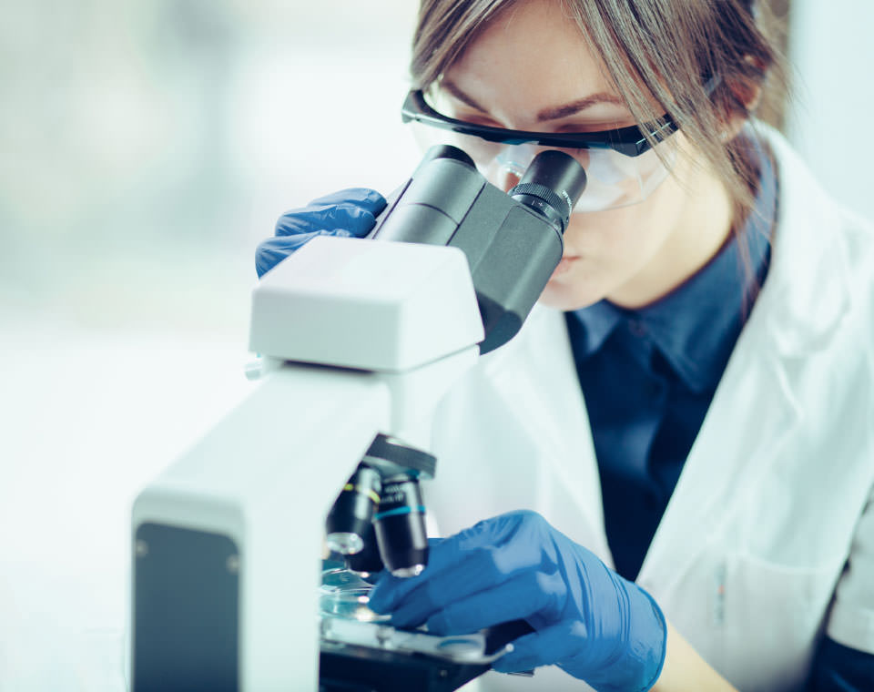 Image of a woman peering through a microscope